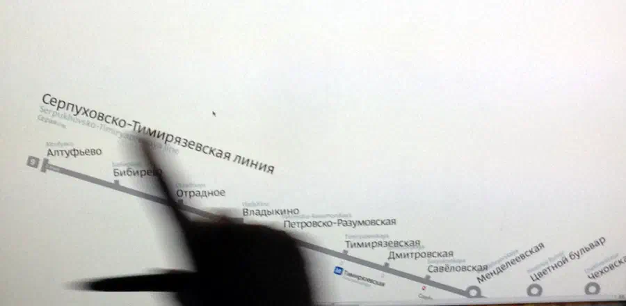 Изображение показывает человека, указывающего на карту на экране компьютера с указанием на нее пальцем. Карта белая по цвету, и рука человека видна с левой стороны экрана.