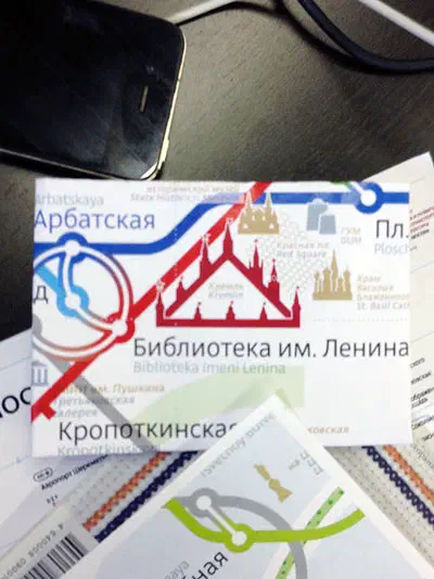 Изображение показывает стол с мобильным телефоном, сидящим сверху, рядом с кучей бумаг и кабельным.