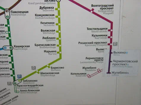 На снимке показана доска с картой московской системы метро. Карта подробно изложена и показывает различные линии и станции системы метро, а также текст с указанием различных остановок и маршрутов.