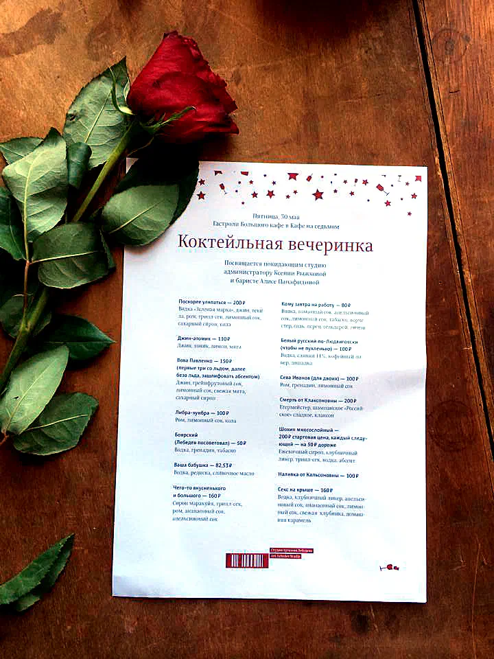 Изображение показывает красную розу, сидящую на деревянном столе, с бумагой с текстом и штрих-кодом рядом с ним. Роза - глубокий красный цвет, а стол - тёплый коричневый цвет.