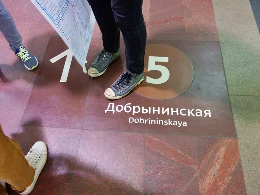 На рисунке два человека стоят рядом друг с другом на полу с надписью "5" и парой обуви. Один человек держит бумагу в руке, а другой стоит на полу.