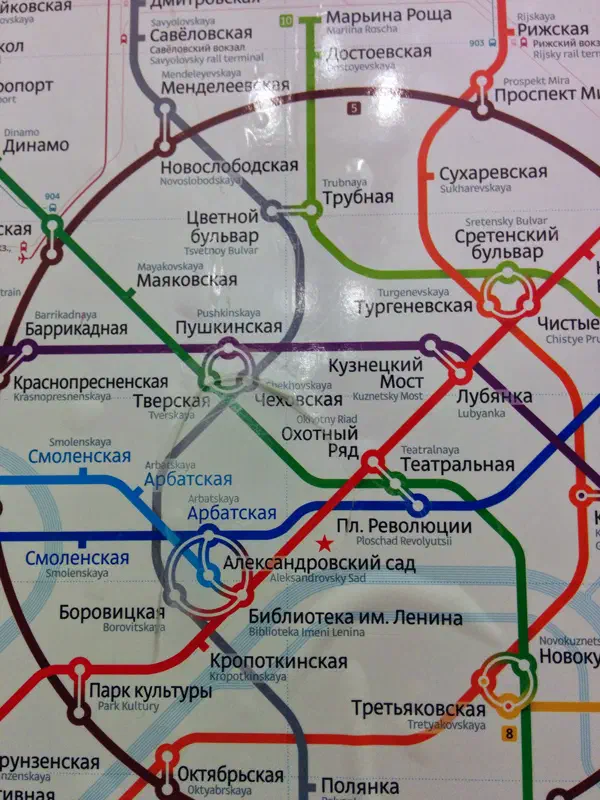 На снимке показана постер метрокарты Московской системы Метро с текстом и линиями, указывающими различные остановки и маршруты города.