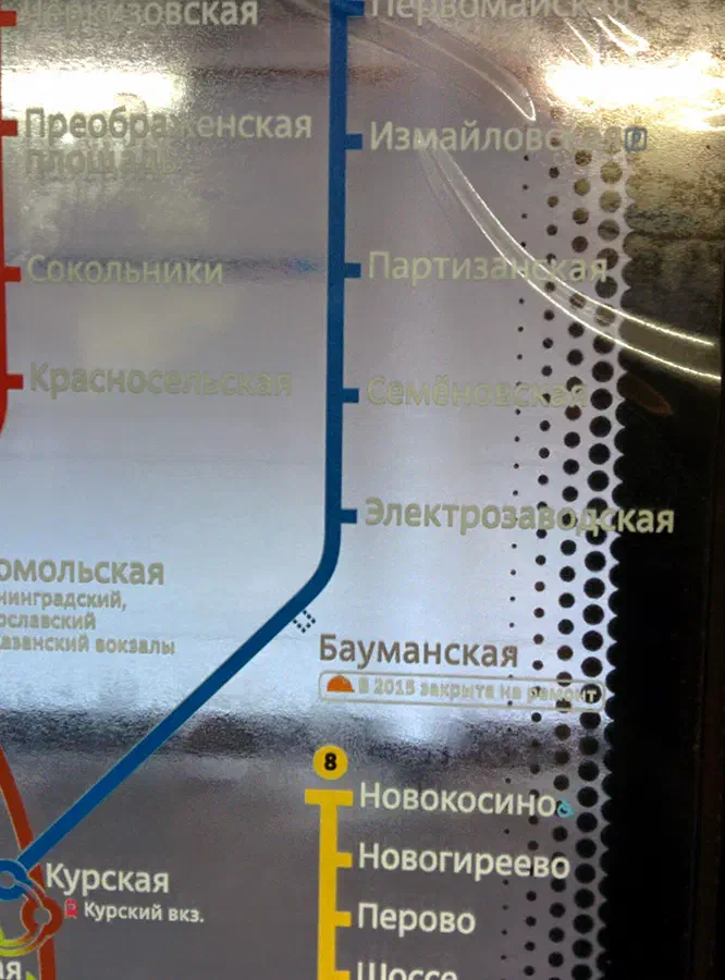 Карта показывает близость металлического знака на стене с картой московской системы метро. Карта подробно изложена и показывает маршрут системы метро с текстом, указывающим различные остановки и маршруты.
