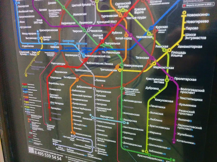 На снимке изображена карта московской системы метро на стене станции метро. Карта заполнена красочными линиями и текстом, содержащими подробную информацию о различных остановках и маршрутах системы метро.