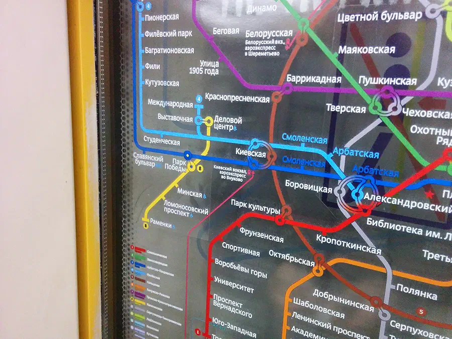 Изображение показывает близость карты на стене станции метро в Москве, Россия. Карта заполнена красочными линиями и текстом, содержащими подробную информацию о системе метро.