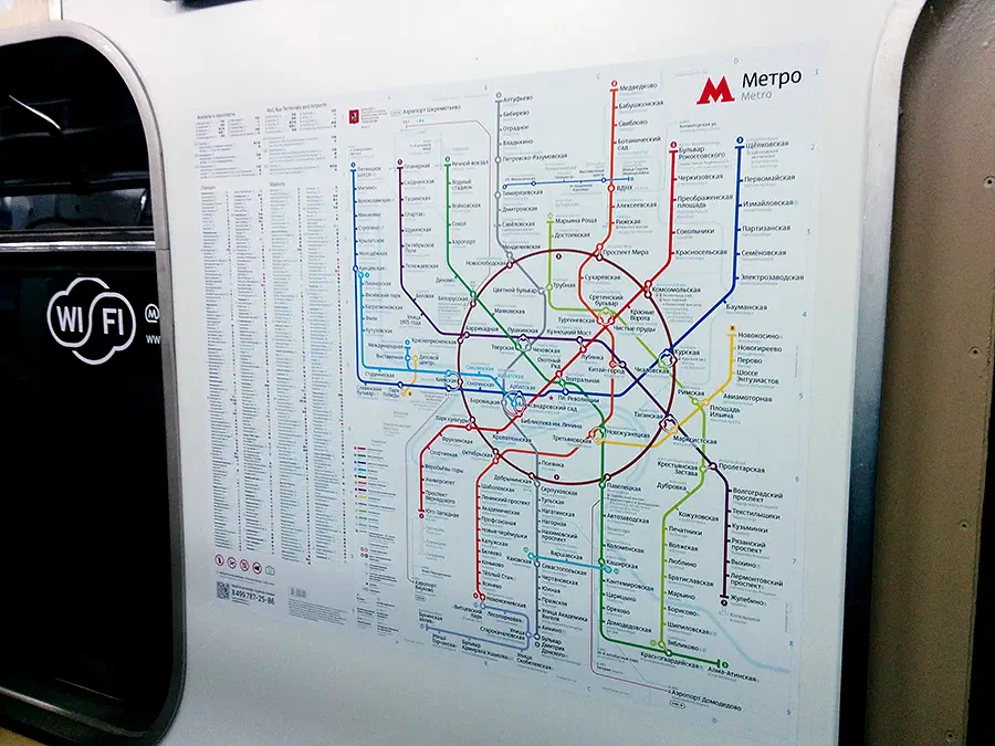 Карта показывает карту московской системы метро на стороне поезда с дверью на левой стороне изображения. Карта представляет собой подробное представление системы метро с различными линиями и
